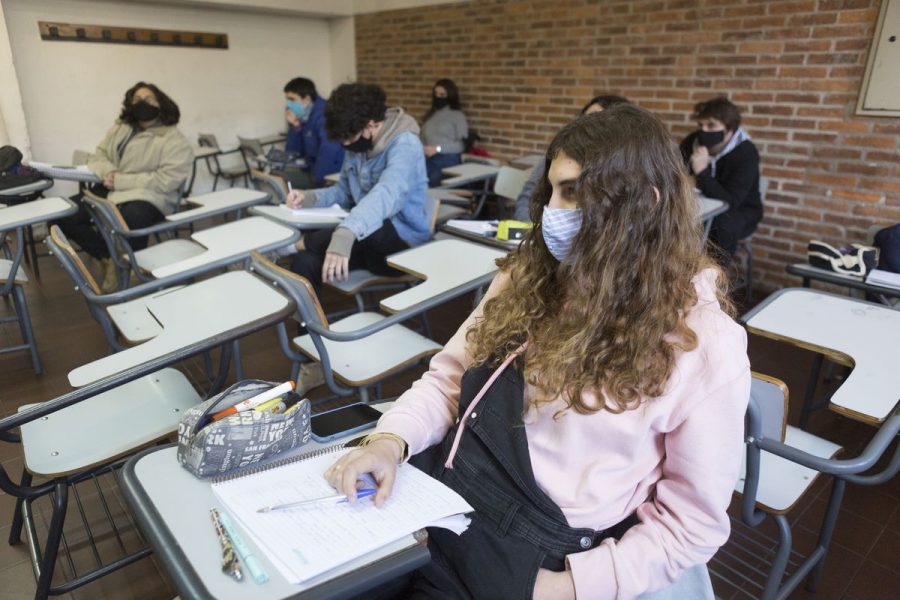 This is a photo of students at a school social distancing and wearing masks.