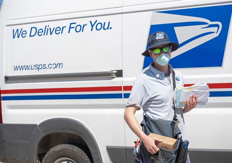 A postal worker in front of his work truck. 