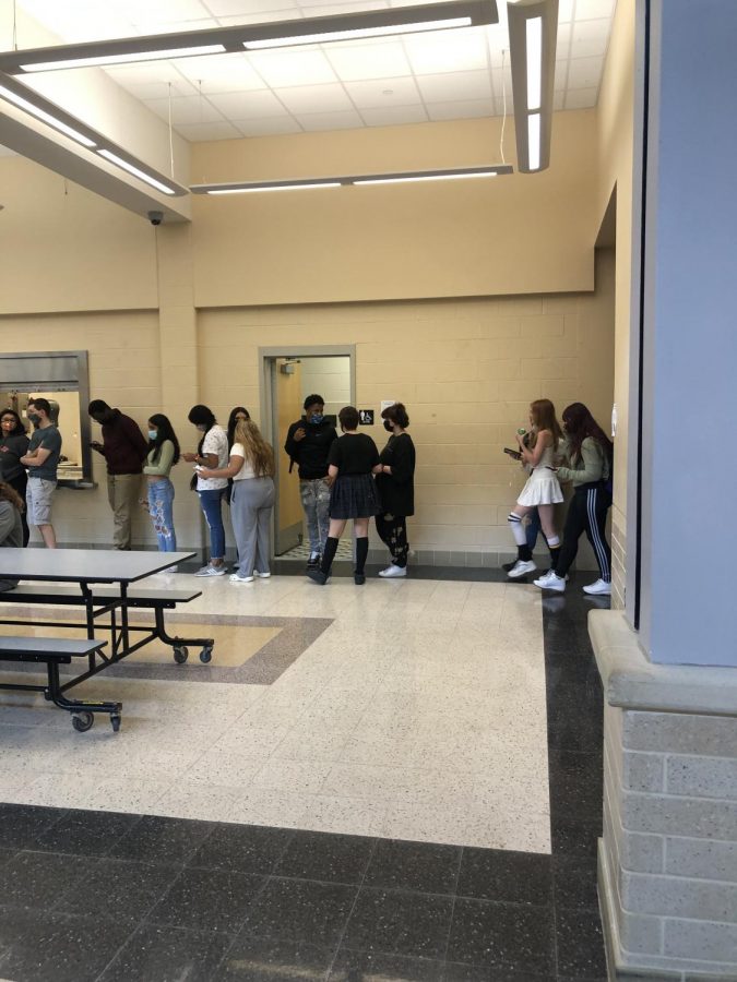 Students wait in a line that goes outside the cafeteria to get lunch.