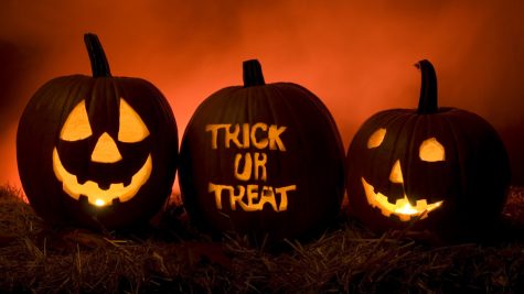 The famous phrase “Trick or treat” carved into a pumpkin next to a jack-o’- lantern.