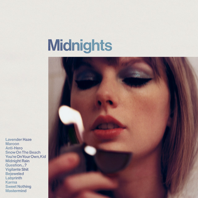The album cover of Taylor Swift’s “Midnights” album featuring an image of her with pretty blue and purple eyeshadow, holding a lighter.