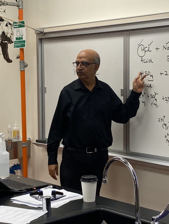  Dr. Shama stands in front of the whiteboard and explains chemistry to his students.
