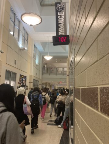  A crowded Oakdale hallway with a clock displaying an early morning time.
