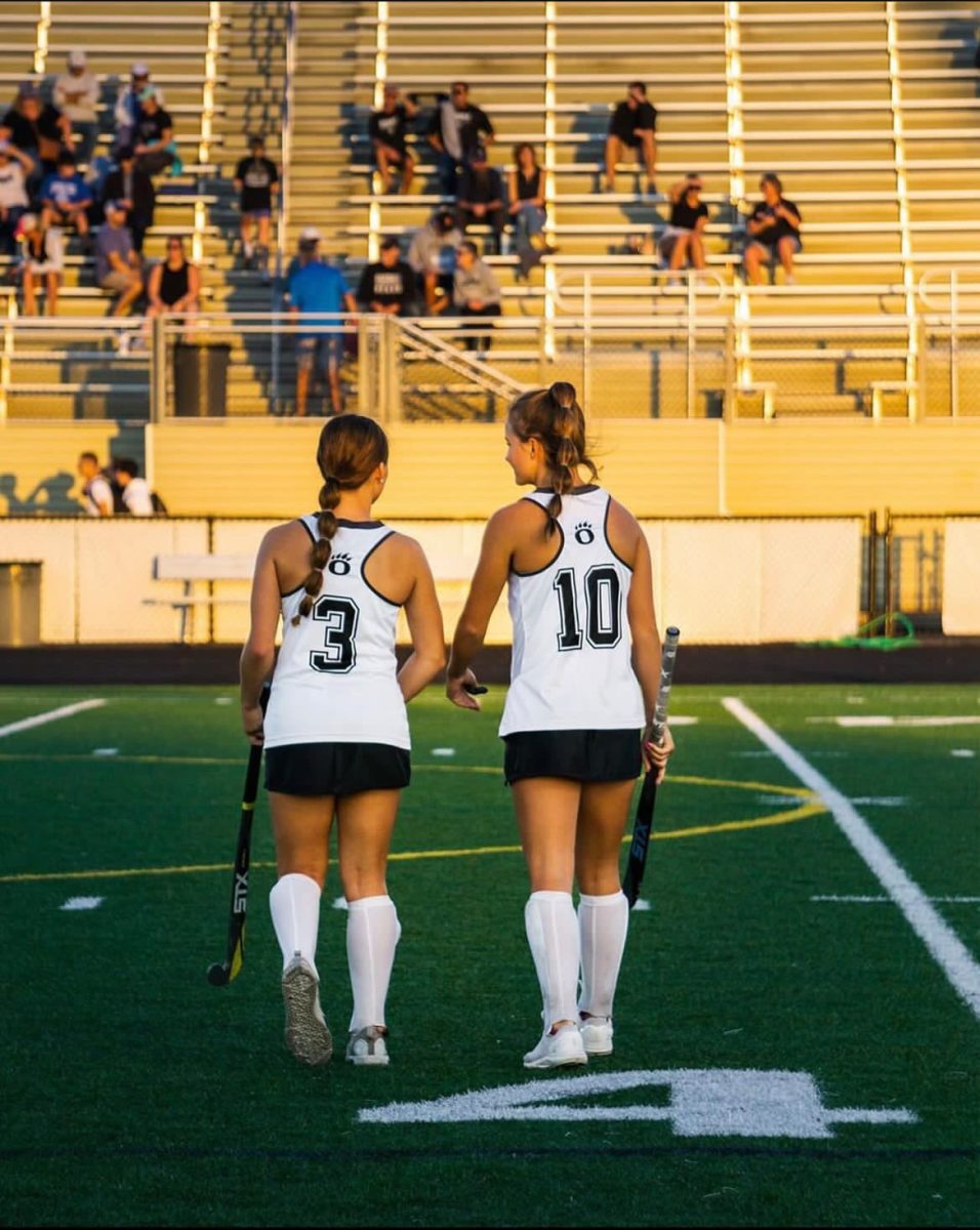Allison Finley #10 and Kate Moore #3 walk out onto the field, to play the second half of a field hockey game.
