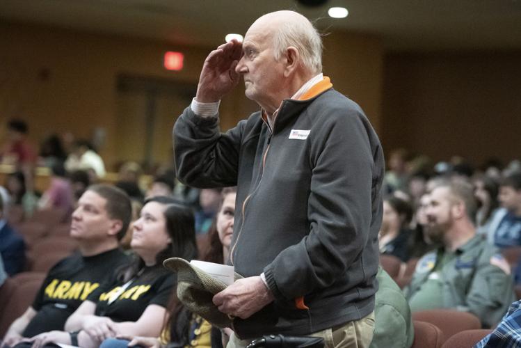 A veteran stands for his branch of the military during the Veterans Assembly held in the auditorium.
