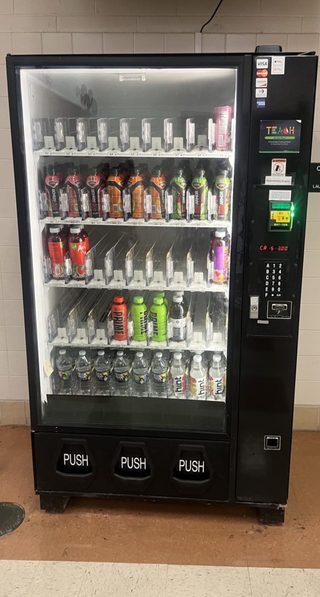 The vending machine in the athletic hallway, filled with all sorts of different beverages.