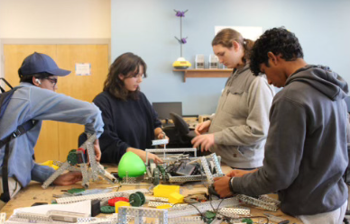 Sophomore Ethan Kumar, Senior Melissa Krajewski, Sophomore Silas Harold, and Sophomore Pranay Mohan, work on assembling this years robot for the competition.