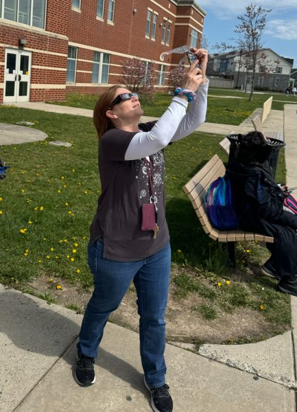 Ms. Brandenburg views the eclipse and attempts to take a picture through the glasses on her phone. 
